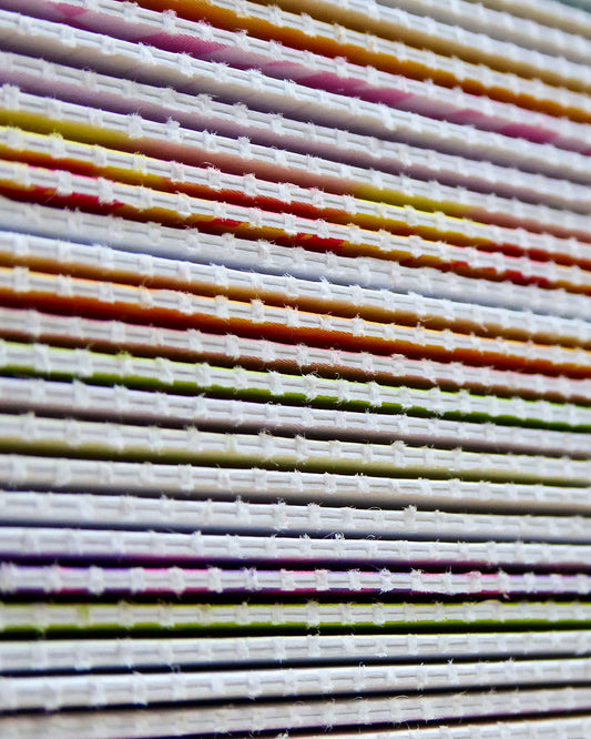 Close-up of stacked reusable greeting cards showing rows of perforated edges in a variety of colourful designs.