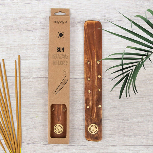 Wooden incense holder with packaging on a light wooden surface with green leaves.